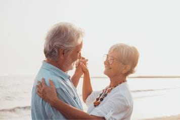 A photo of a female audiologist providing a hearing aid consultation to a middle-aged male client with brown skin and a beard.